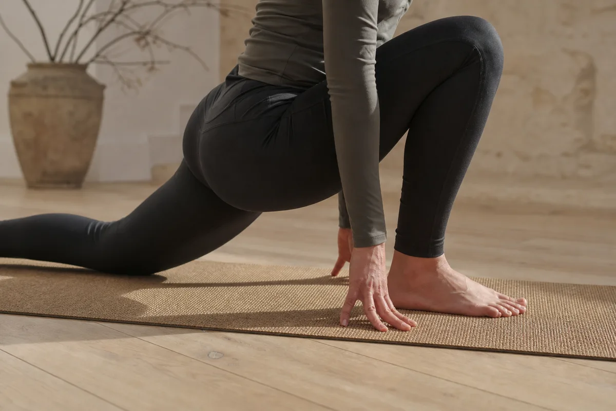 Étirement profond des hanches sur un tapis de yoga en fibres naturelles